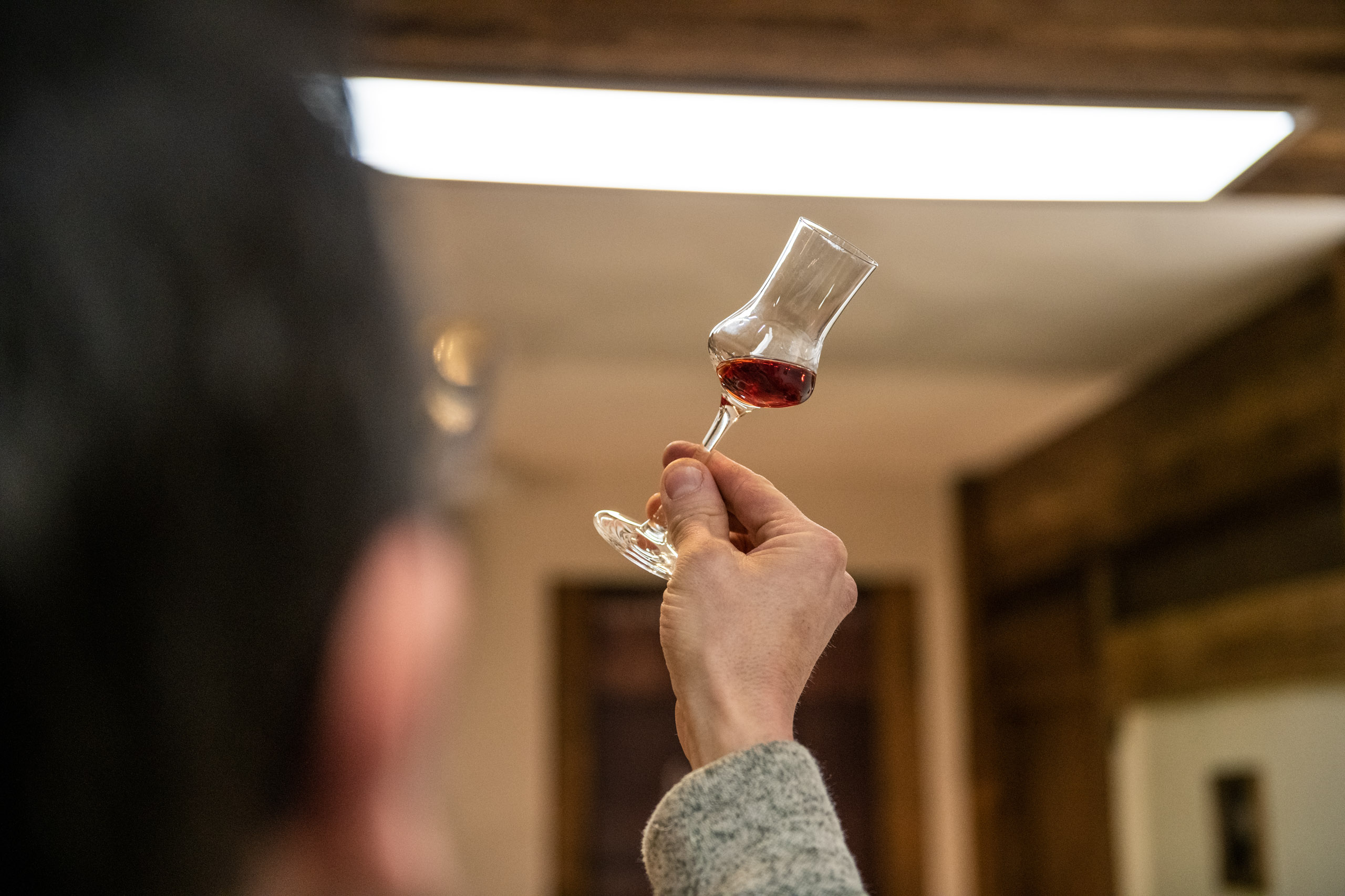 Toni Lackner mit einem Zirbenschnaps im Glas in der Schnapsbrennerei.